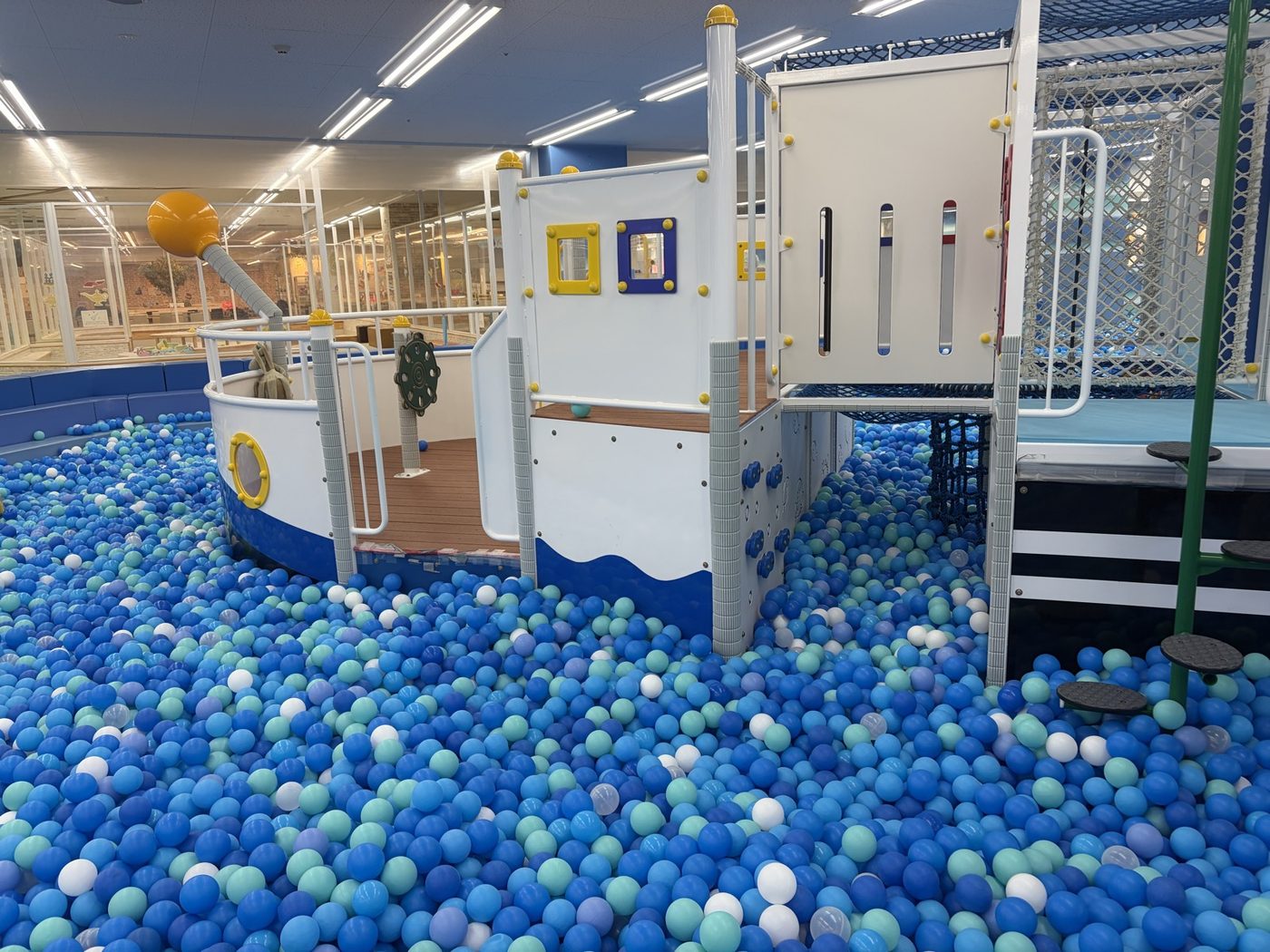ピュアハートキッズランド ポンテポルタ千住店のボールプール「キッズラグーン」。青いボールが敷き詰められ、中央に船の形をした大型遊具がある