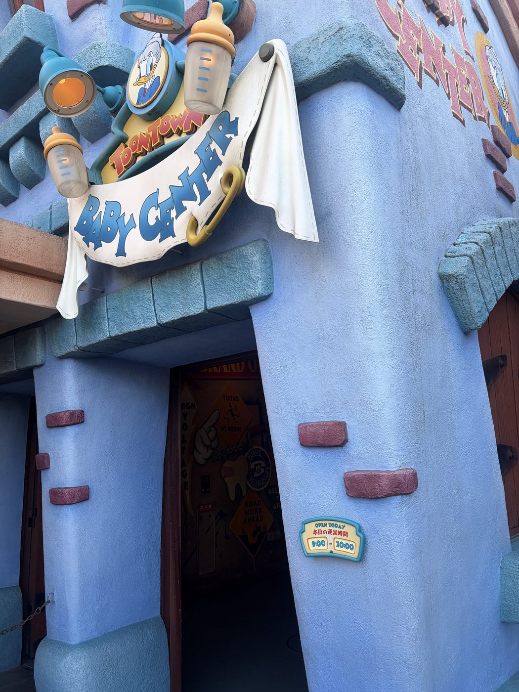 東京ディズニーランド トゥーンタウンのベビーセンター入口。哺乳びんの看板の下に「OPEN TODAY 本日の運営時間 9:00 - 20:00」の掲示がある