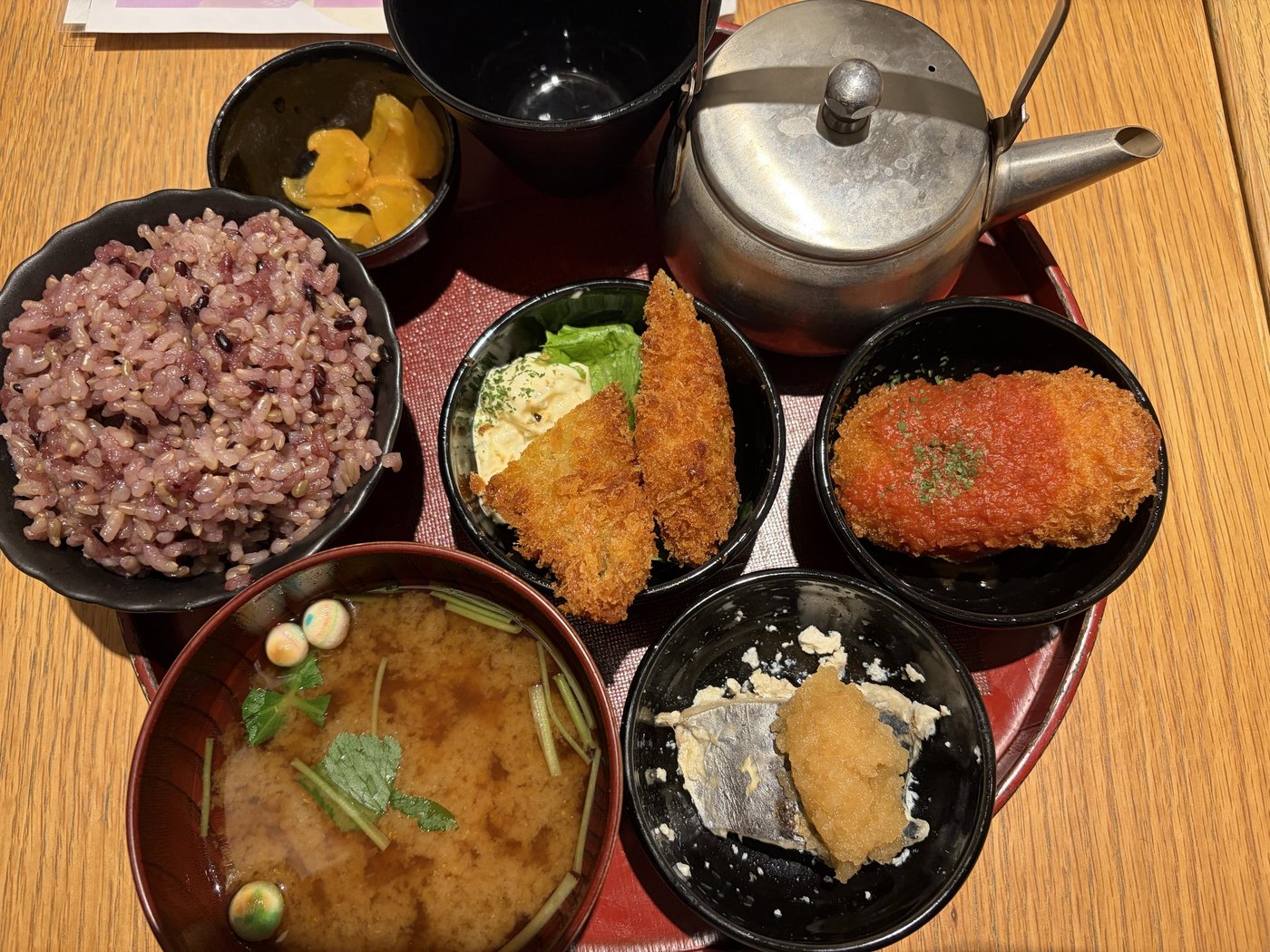 至福のごはん。黒米ブレンドの玄米ごはん、味噌汁、漬物、フライやさわらと大根おろしなど小鉢3品、ほうじ茶のポット
