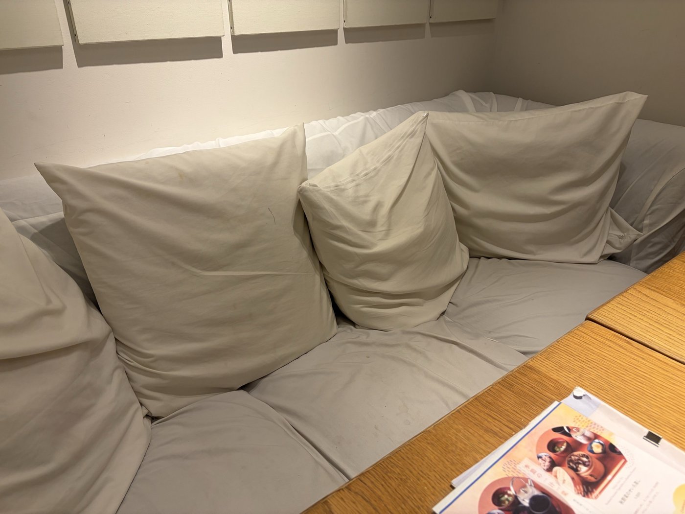 24/7 cafe apartment 有楽町のソファー席。白いソファーに大きなクッションが並び、横に仕切りがない